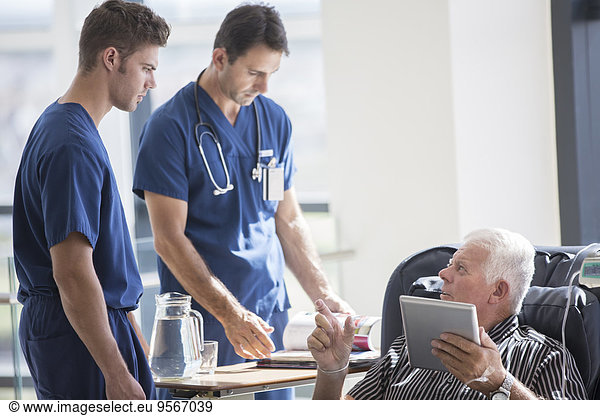Patient using tablet pc and talking to doctors in hospital