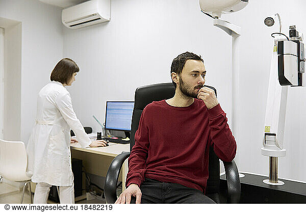 Patient with hand on chin waiting in clinic