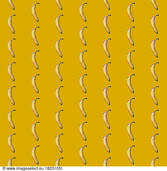 Pattern of bananas flat laid against yellow background