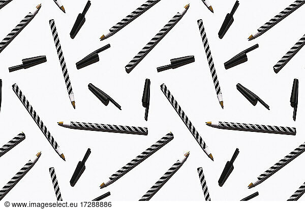 Pattern of black and white striped pens flat laid against white background