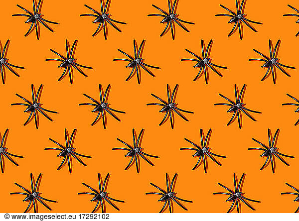 Pattern of black spiders against orange background