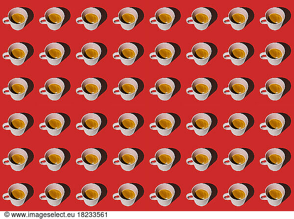 Pattern of cups of coffee standing in rows against red background