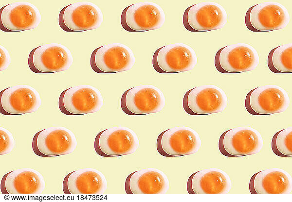 Pattern of egg shaped candy flat laid against yellow background