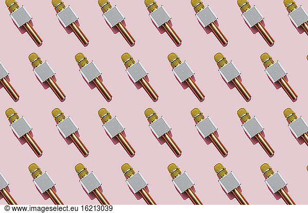 Pattern of golden microphones against pink background