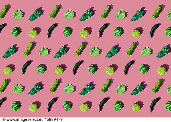 Pattern of green plastic vegetables against pink background