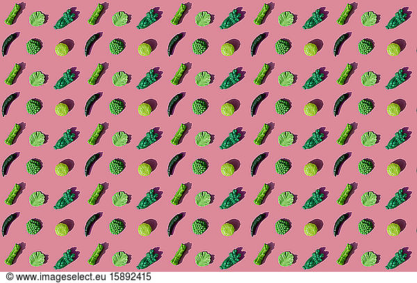 Pattern of green plastic vegetables against pink background