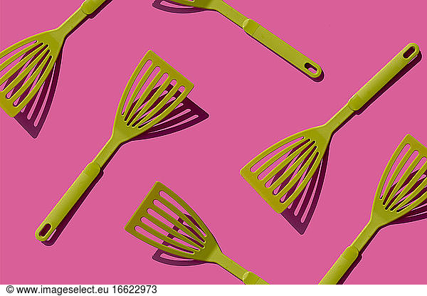 Pattern of green spatulas against pink background