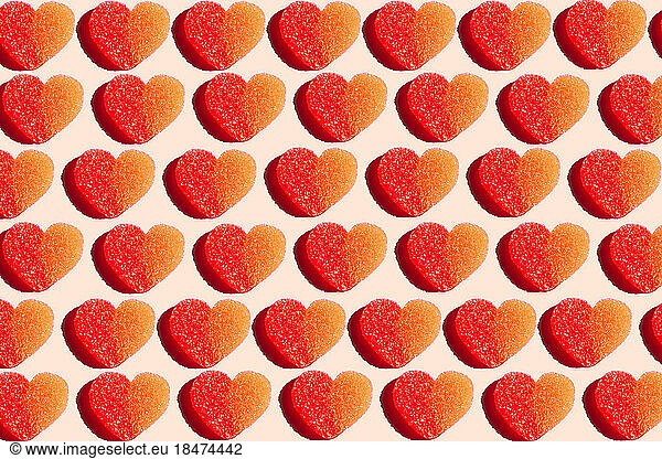 Pattern of heart shaped candy flat laid against yellow background
