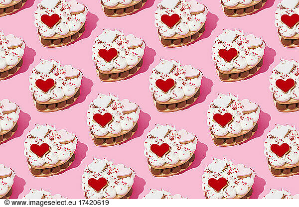 Pattern of heart shaped cookie cakes flat laid against pink background