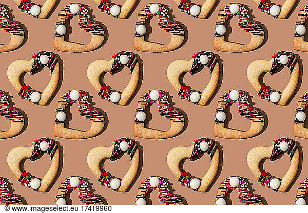 Pattern of heart shaped cookies flat laid against brown background