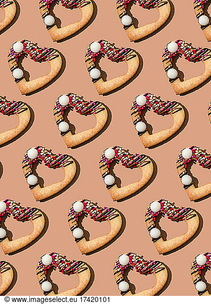 Pattern of heart shaped cookies flat laid against brown background