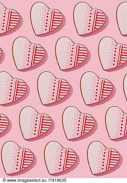 Pattern of heart shaped cookies flat laid against pink background