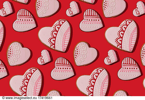 Pattern of heart shaped cookies flat laid against red background