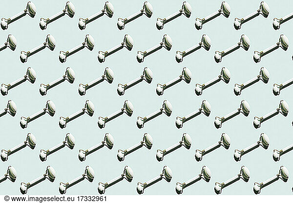 Pattern of marble jade rollers flat laid against mint green background