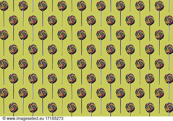 Pattern of multi colored lollipops against yellow background