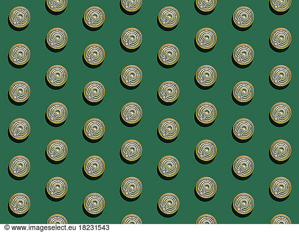 Pattern of rows of cans flat laid against green background