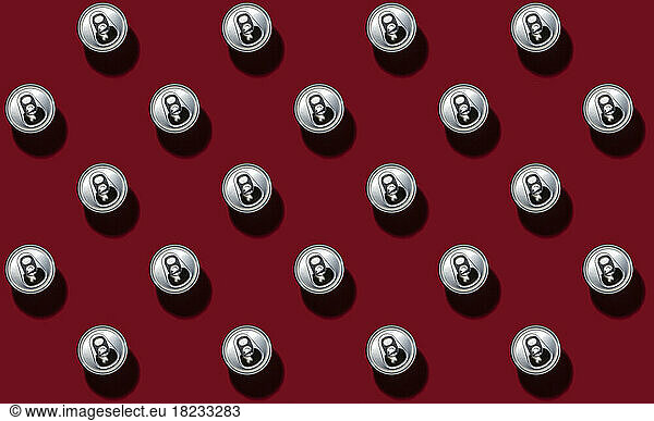 Pattern of rows of drink cans standing against red background