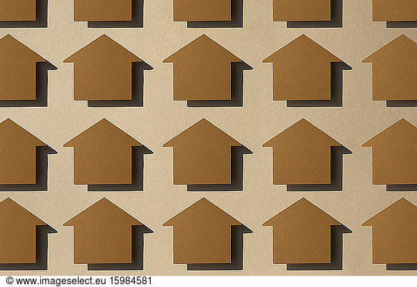 Pattern of rows of house shaped paper cuts against brown background