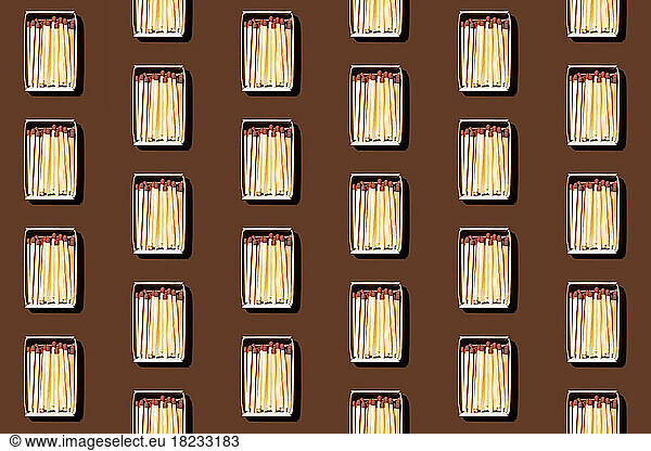 Pattern of rows of matchboxes flat laid against brown background
