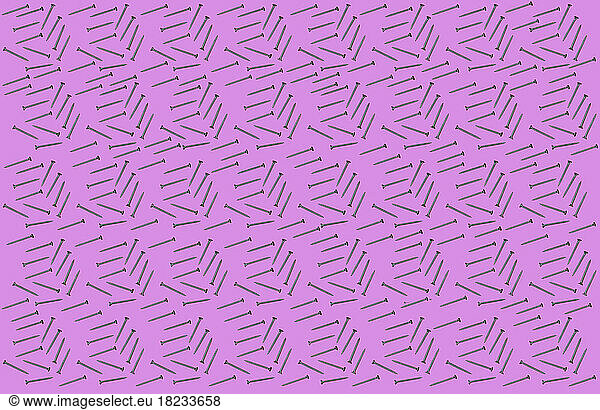 Pattern of rows of screws flat laid against pink background
