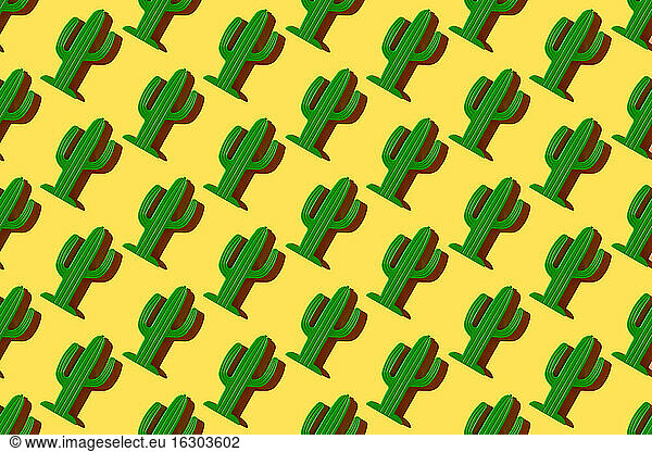 Pattern of small plastic cacti against yellow background