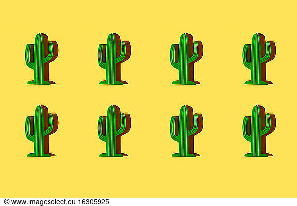 Pattern of small plastic cacti against yellow background