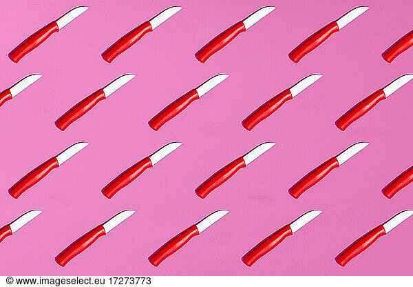 Pattern of table knives on pink background