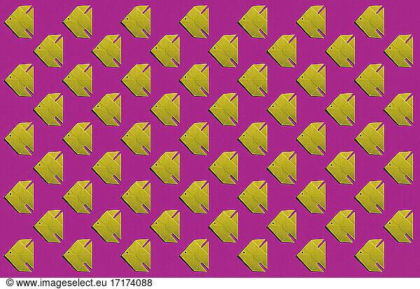 Pattern of yellow origami fish against pink background