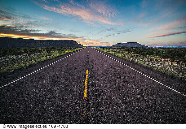 Paved road with yellow stripes in Big Bend National Park during sunset