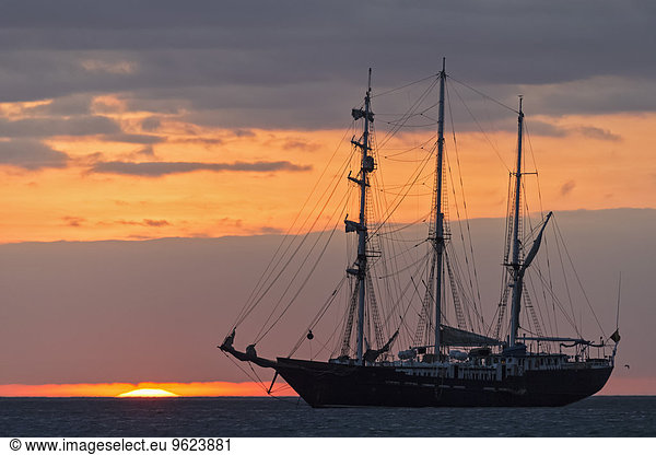 Pazifischer Ozean  Segelschiff auf den Galapagosinseln bei Sonnenuntergang