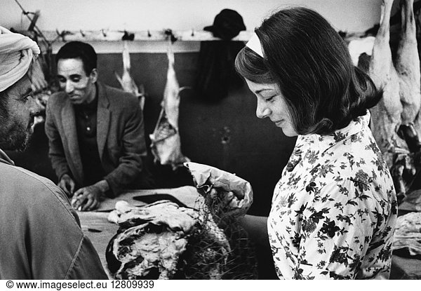 PEACE CORPS: MOROCCO. Peace Corps volunteer Marlene Manske buying meat from a village market in Morocco. Photograph  1966.