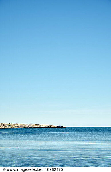 Peaceful blue sea with rocky coast under cloudless sky