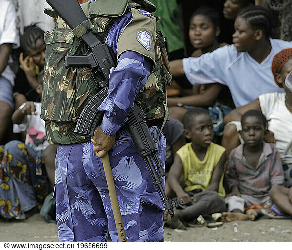 Peacekeeper with machine gun infront of group of kids
