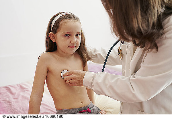 Pediatric doctor examine little happy girl with stethoscope. Chi