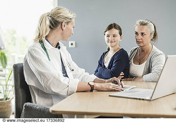 Pediatrician and woman having discussion while sitting at doctor's office