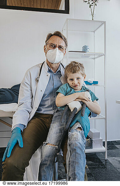Pediatrician sitting with boy on lap at examination room