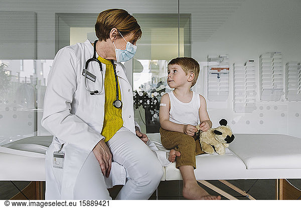 Pediatrician with face mask and toddler in medical practice