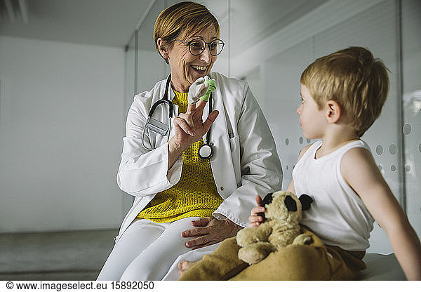 Peditrician with finger dolls and toddler in medical practice