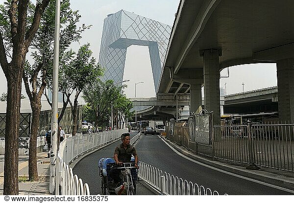 Peking  China  Asien - Straßenszene mit Radfahrer im zentralen Geschäftsviertel Guomao der chinesischen Hauptstadt und dem neuen Gebäude der CCTV-Zentrale im Hintergrund.