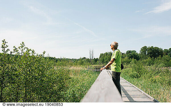 pensioner enjoying the view walking on a boardwalk in the countryside