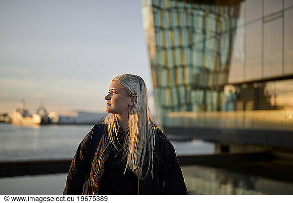 Pensive blond lady on seaside against building