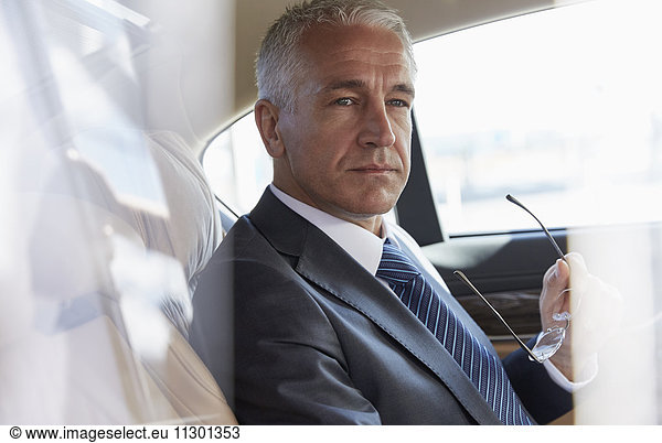 Pensive businessman riding in back seat of town car