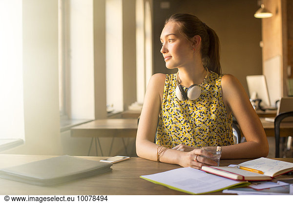 Pensive casual businesswoman with headphones looking away in office