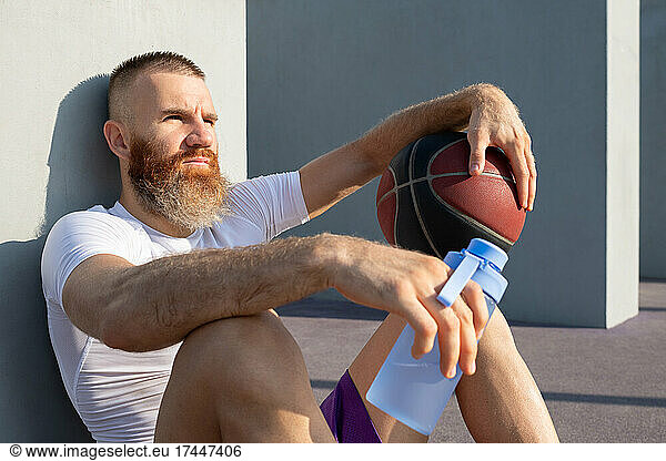 Pensive male basketball player with bottle of water