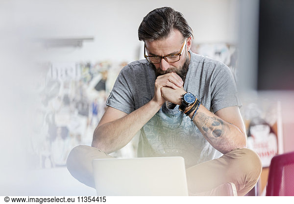 Pensive male design professional working at laptop