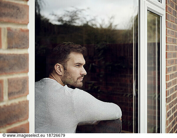 Pensive man looking out of the window at home