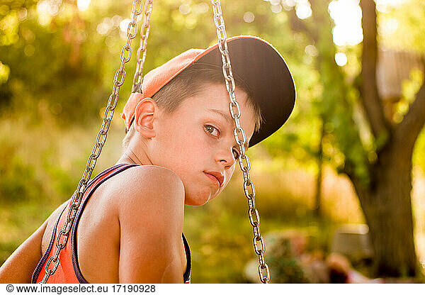 Pensive teenager on a swing in summer