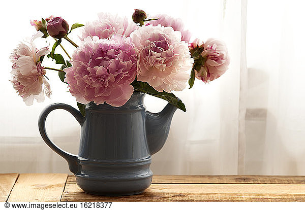 Peonies in vase on wooden table  close up