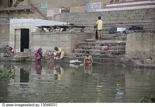 People bathing and washing clothes in river by steps