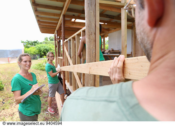 People building wooden house frame together